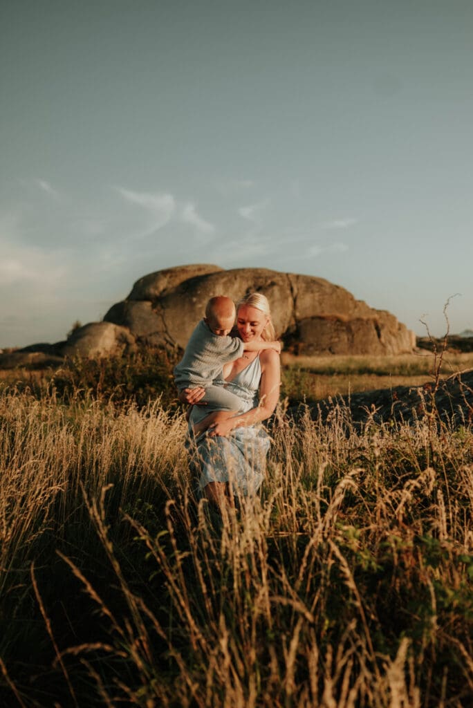 Mamma som går med sin son i famnen vid stranden på Öckerö.