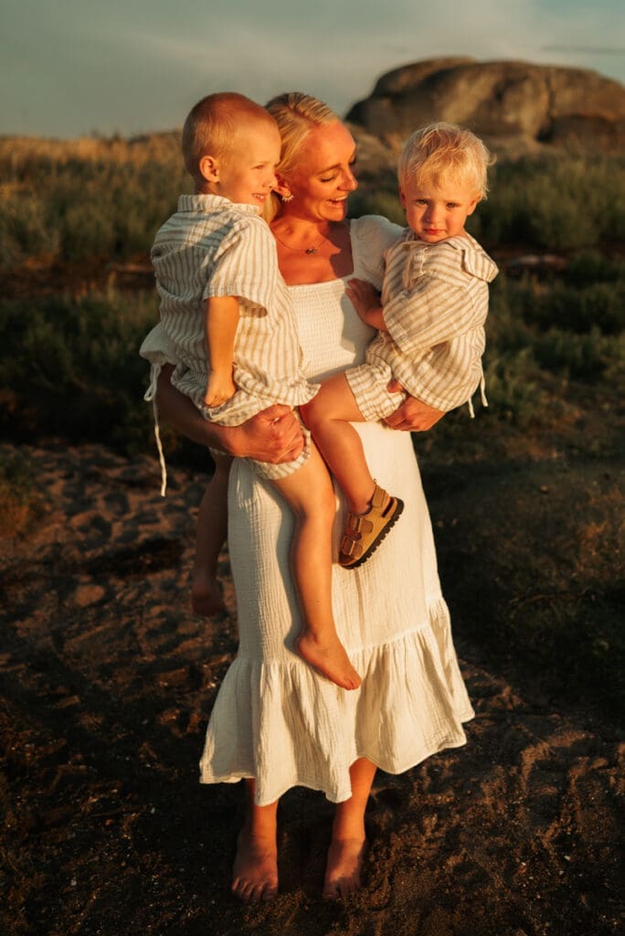 En mamma håller sina två pojkar i famnen i solnedgången på Öckerö.