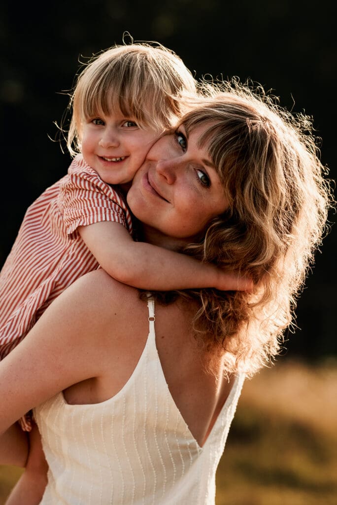 Mamma som håller sin dotter nära i famnen i solnedgången i Lerum.